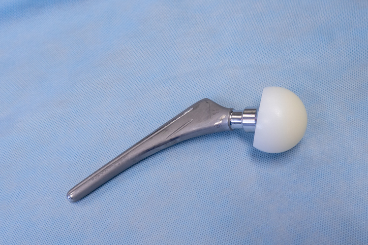 an explanted surgical hip prosthesis lies on an operating table